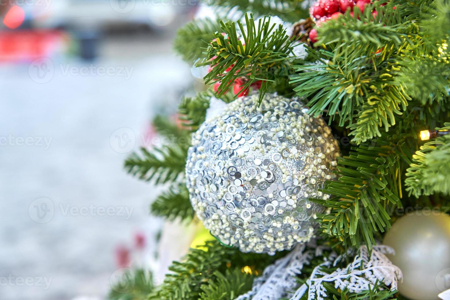 close up of christmas tree decorated with silferr sparkling balls and garland with lights on. Festive background with copy space for your projects photo
