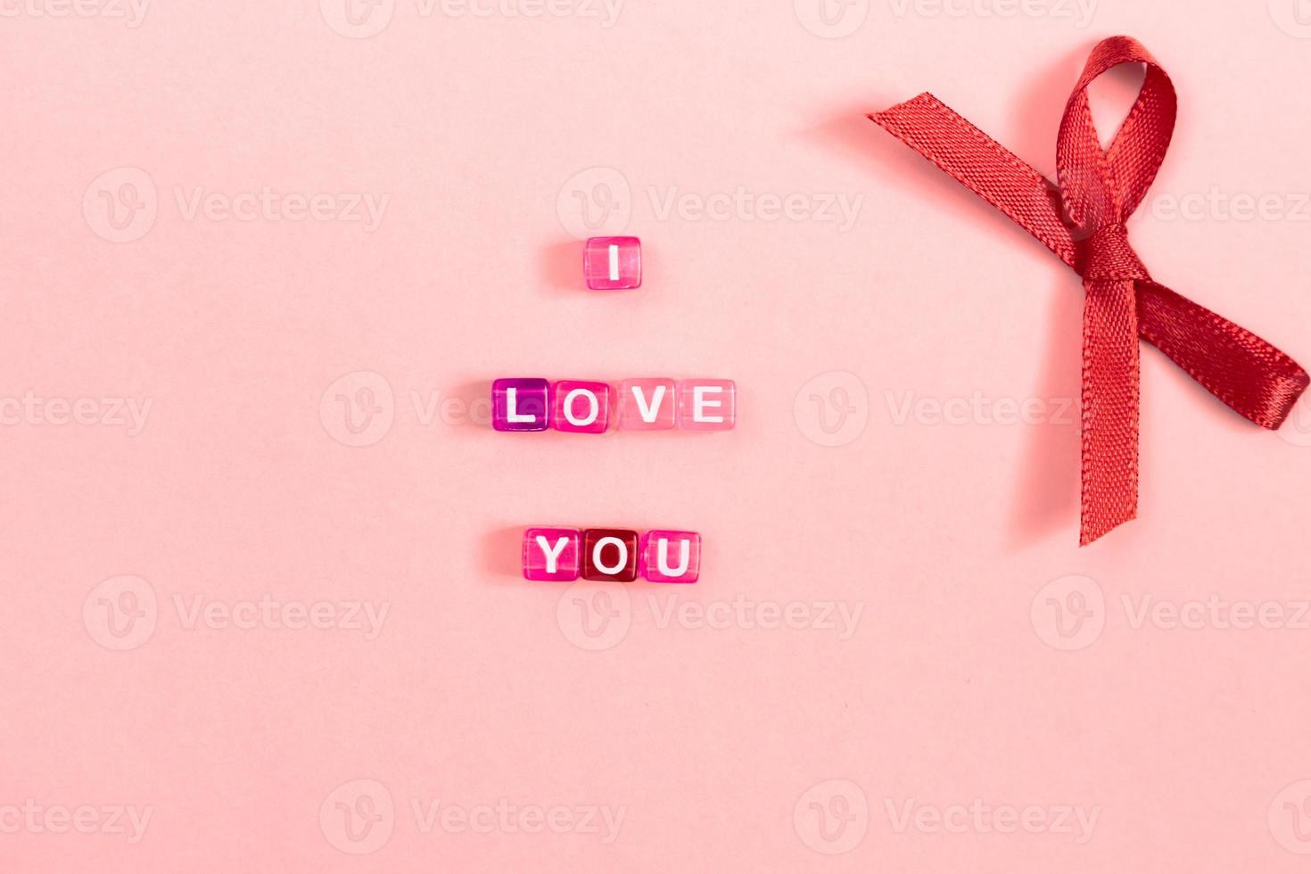 Love you  inscription made of colorful cube beads with letters. Festive pink background concept with copy space photo