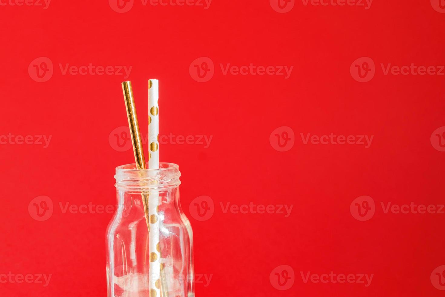 Zero waste. Paper recycable drinking cocktail party straws in glass vintage bottle on red background. photo