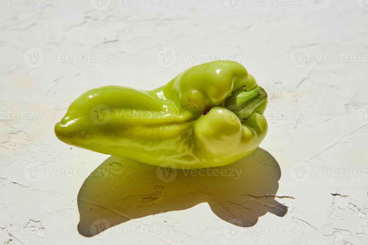Trendy ugly organic green bell pepper with spots on white backgeound. Hard light. photo
