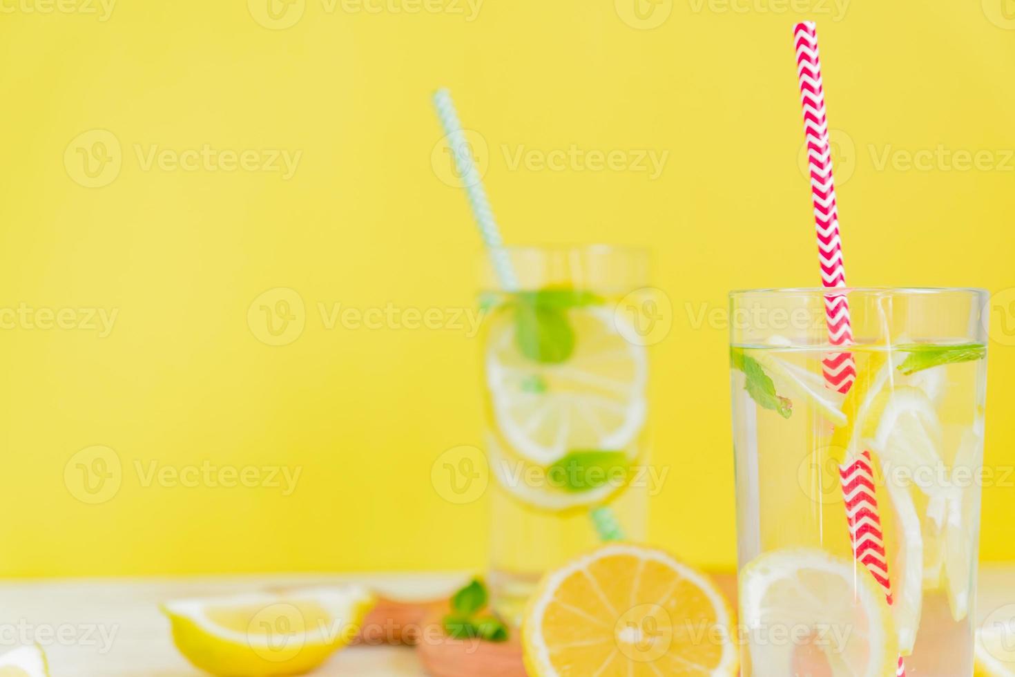Homemade lemonade with lemon and mint on colored yellow background. Summer cold drink cocktail. Copyspace photo