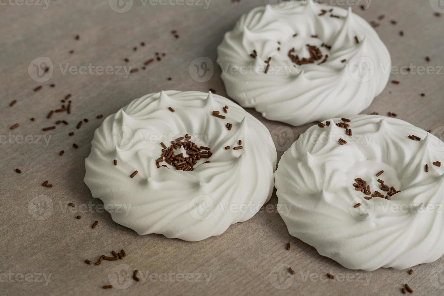 merengues caseros de aire blanco y decoraciones de confitería en papel pergamino. foto