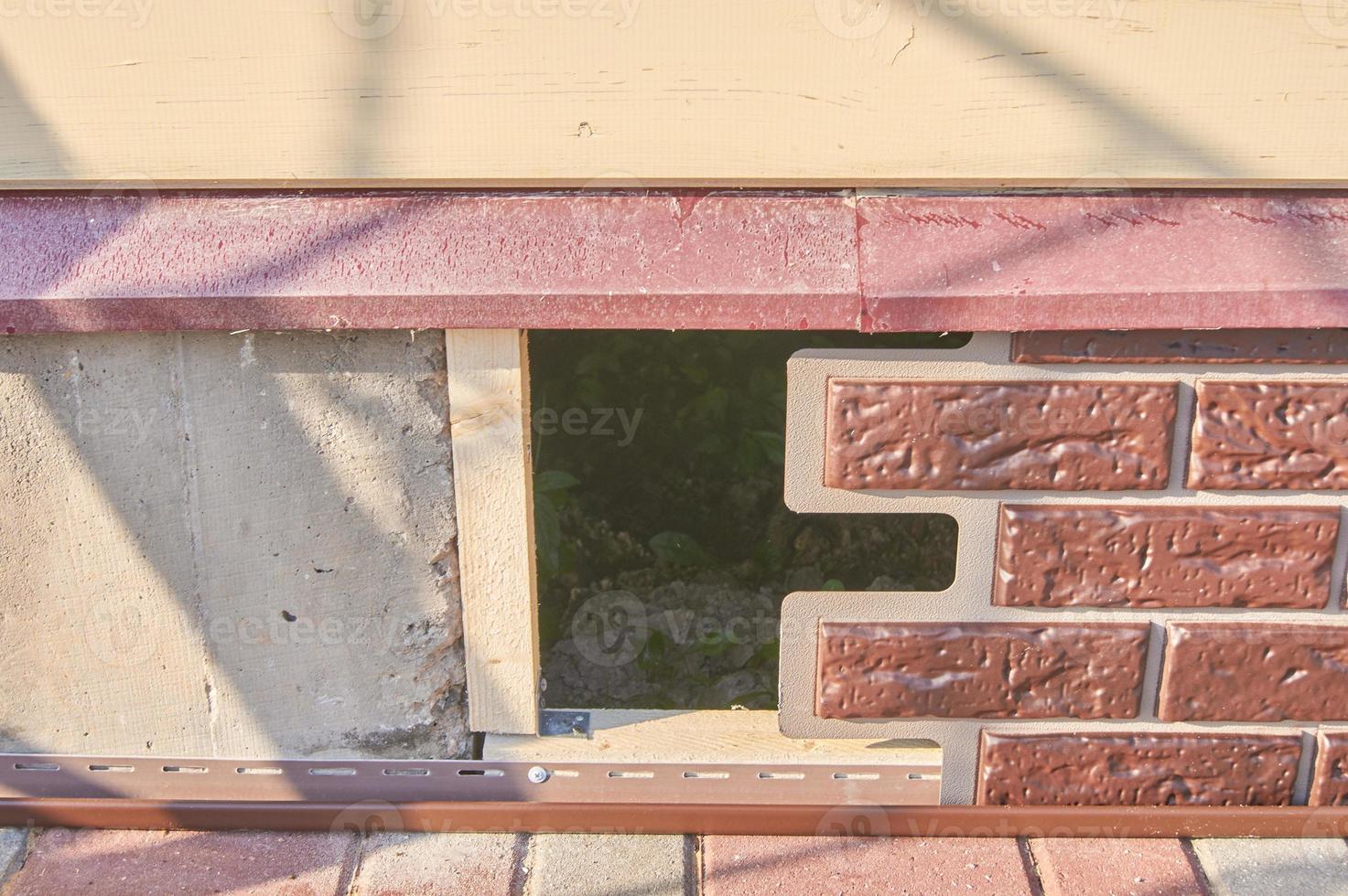 A worker installs panels brown siding on the facade of the house photo