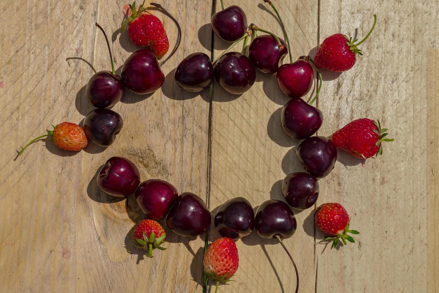 ripe juicy cherry and strawberry on wooden background photo