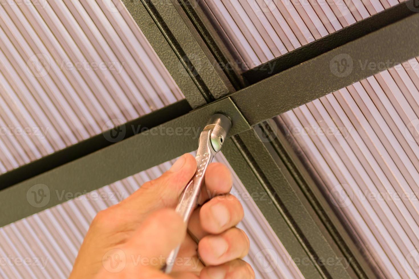 male hands holding socket wrench fixing roof made of polycarbonate photo
