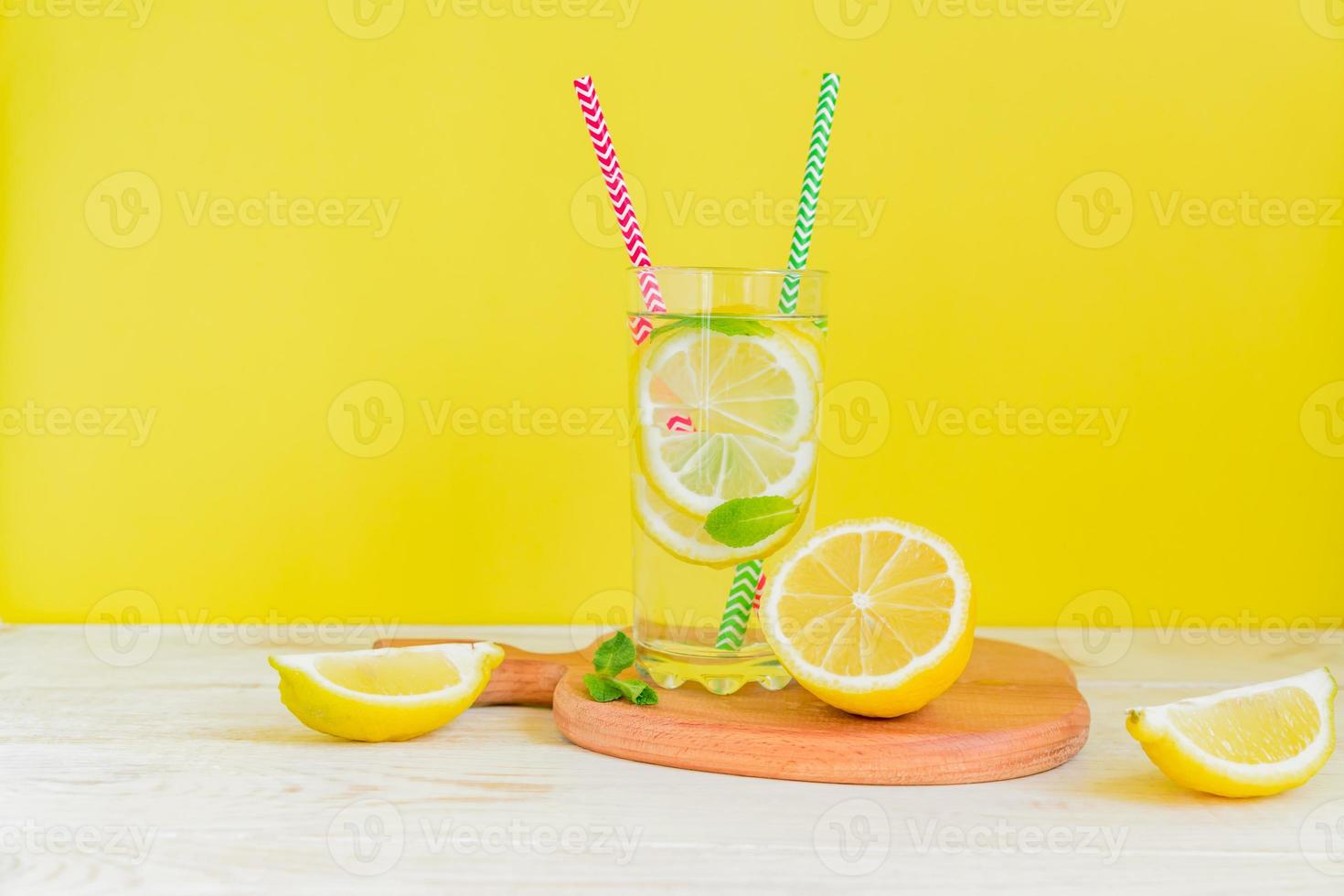 Homemade lemonade with lemon and mint on colored yellow background. Summer cold drink cocktail. Copyspace photo