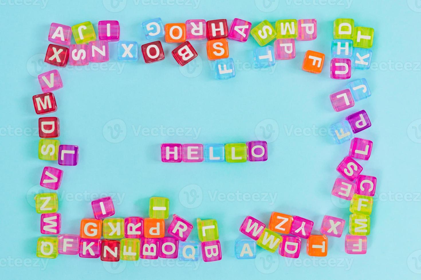 Hello inscription made of colorful cube beads with letters. Festive blue background concept with copy space photo