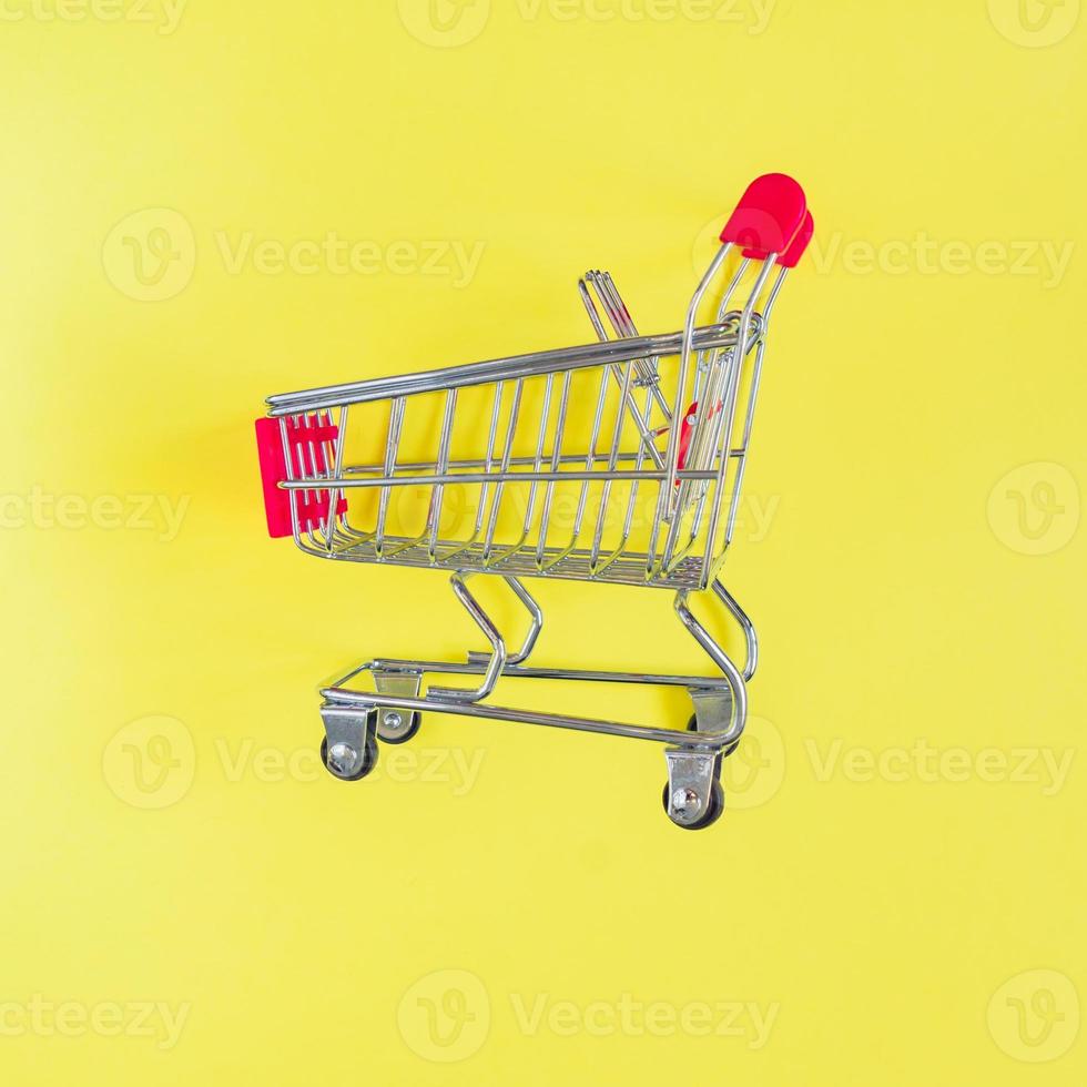 Empty shopping cart on yellow background. Top view, minimal flat lay. photo