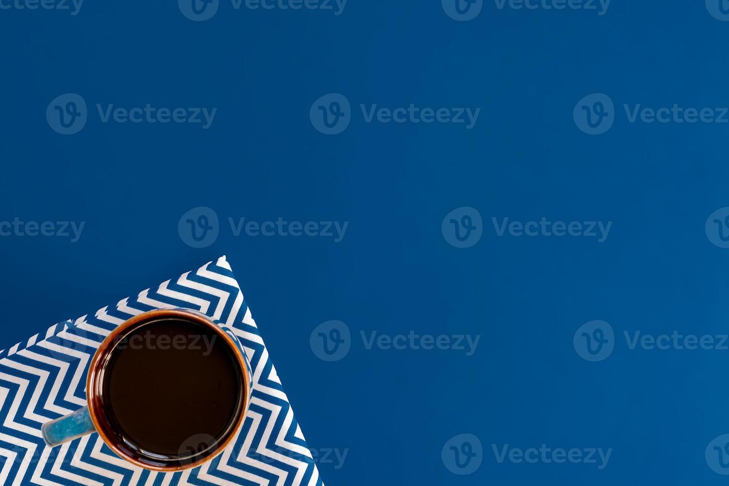 top view of cup of black coffe on blue background with copy space. photo