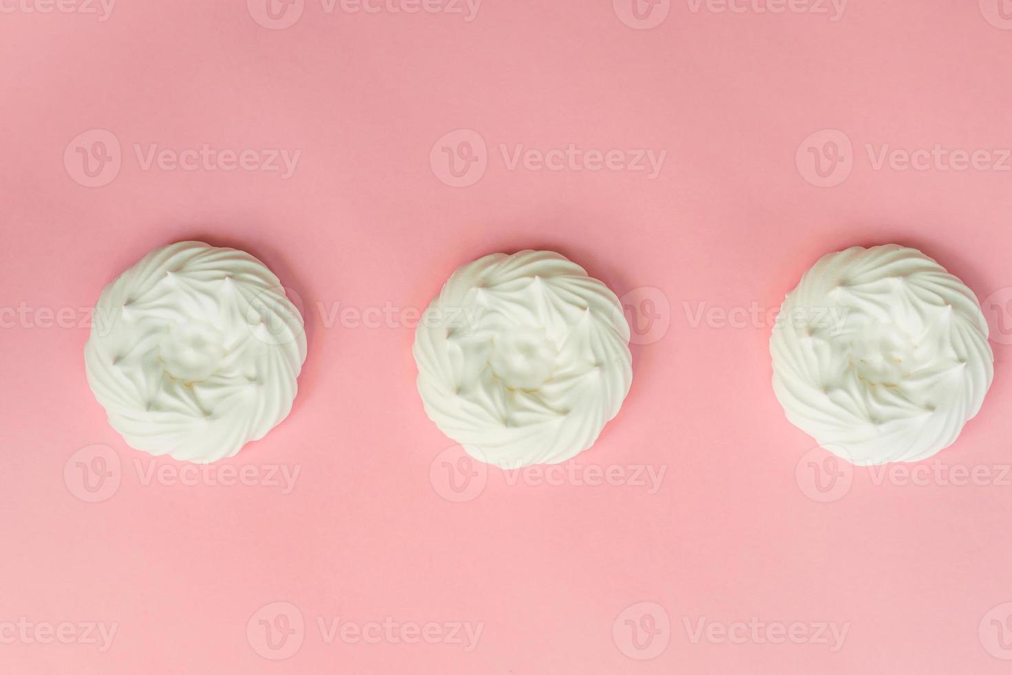 top view of homemade white air meringues on pink background photo