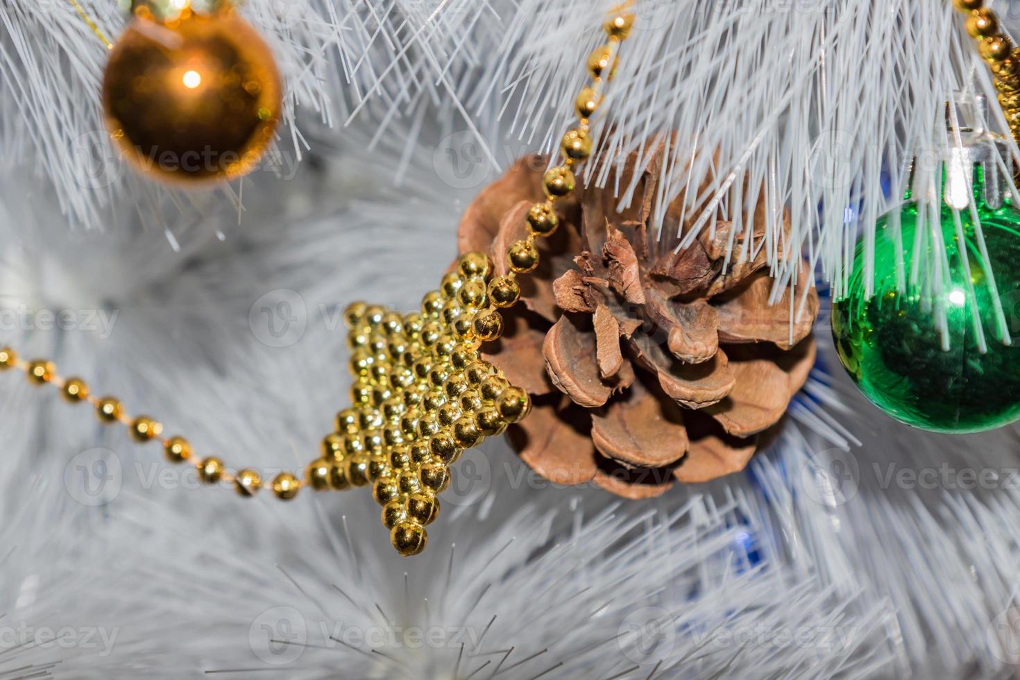 holidays, new year and celebration concept - white Christmas tree. golden and blue garland, pine cone, green and golden balls photo