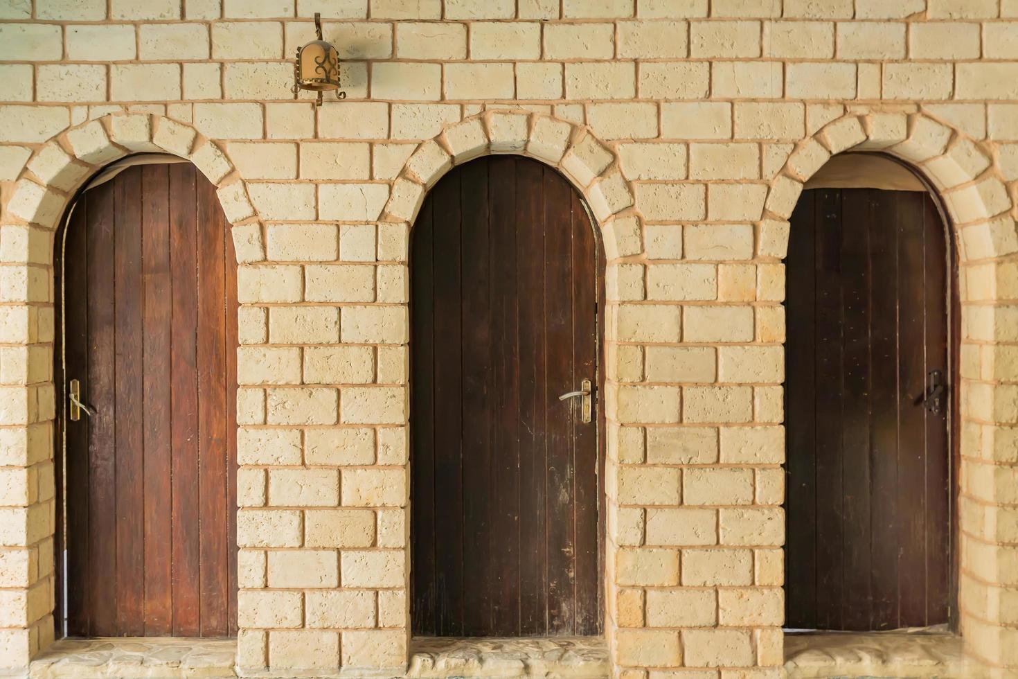 close up of three wooden doors and white brick wall photo