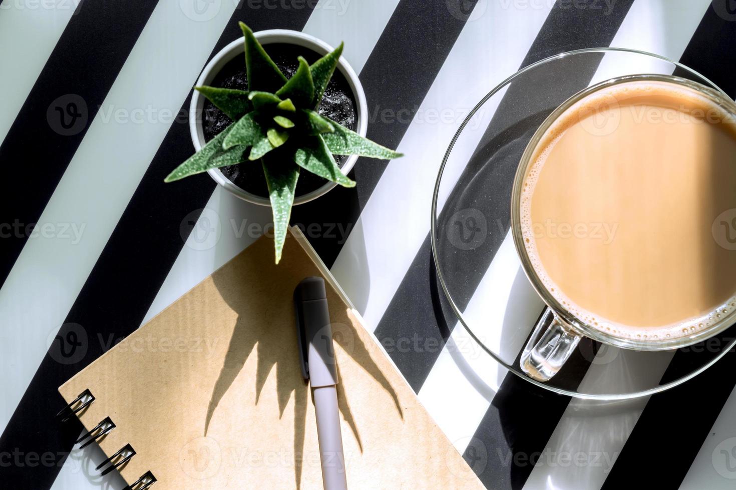 Stylish minimalistic workspace with notebook, pen, cup of coffee and succulent on striped black and white background. Flat lay style Top view. photo