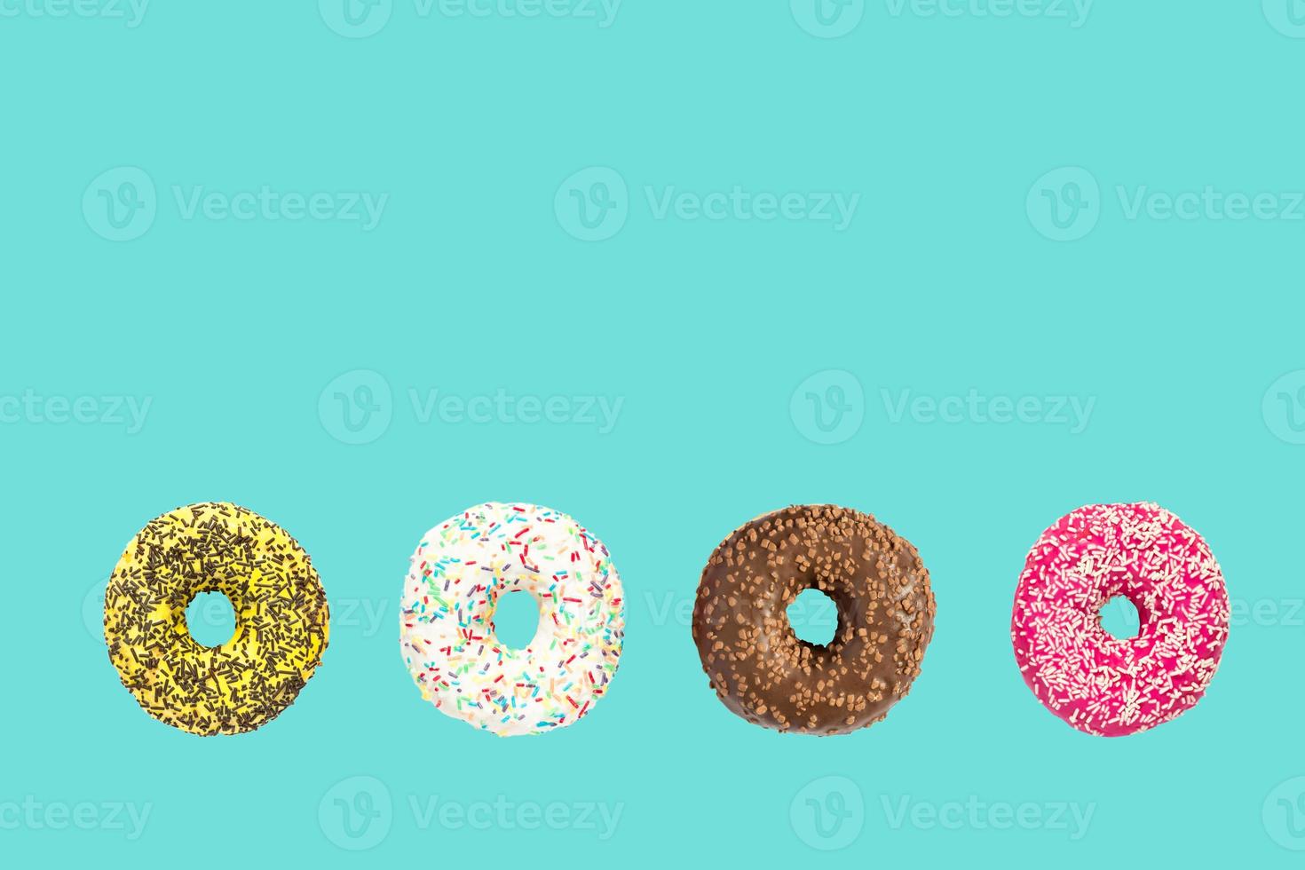 multicolored frosted donuts with colorful sprinkles  and hazels on blue background. photo