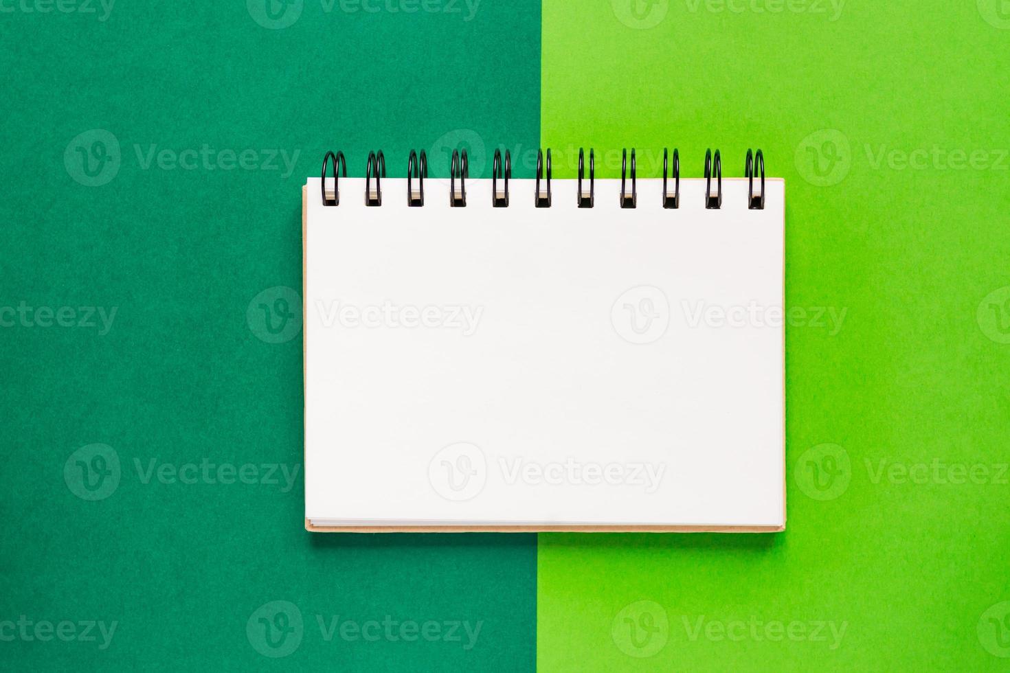 Top view of open empty spiral notebook on green colorful background photo
