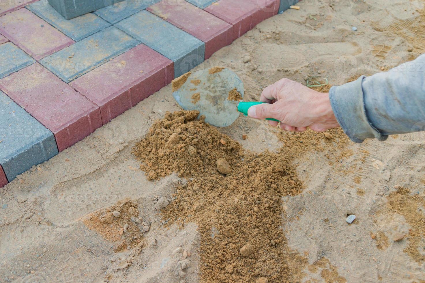 Worker laying red and gray concrete paving blocks. Road Paving, construction. photo