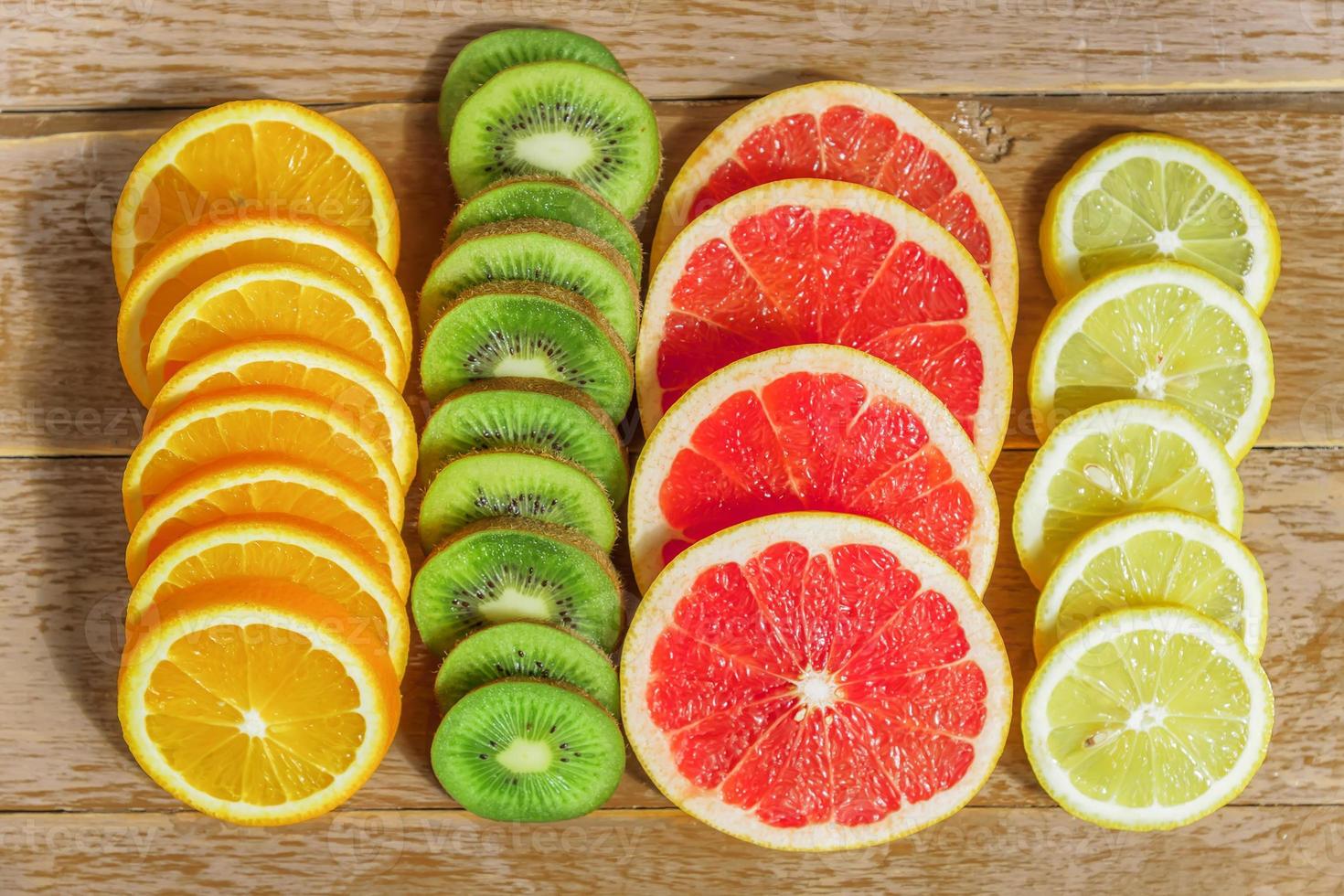 frame with slice of oranges, lemons, kiwi, grapefruit pattern on wooden background. copy space. photo