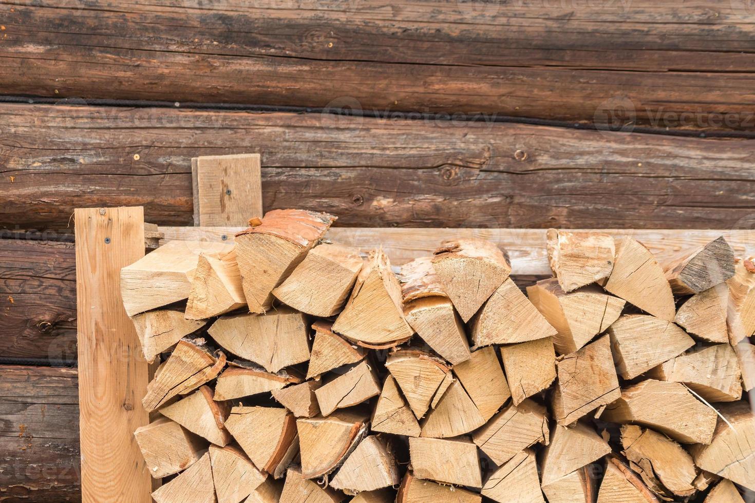 stack of firewood on log wall background. outdoor storage of woodpile photo