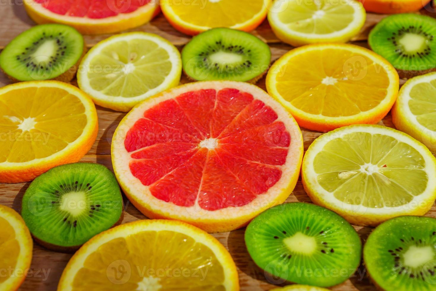 frame with slices of oranges, lemons, kiwi, grapefruit pattern on wooden background. Copy space photo