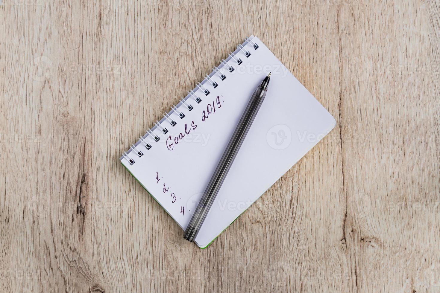 Business and office concept - blank notebook and black pen on wooden table. Goals 2019. Minimal flat lay, top view. photo