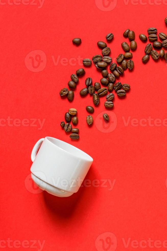 Top view of fresh roasted coffe beans and whte cup on red background. Flat lay. photo