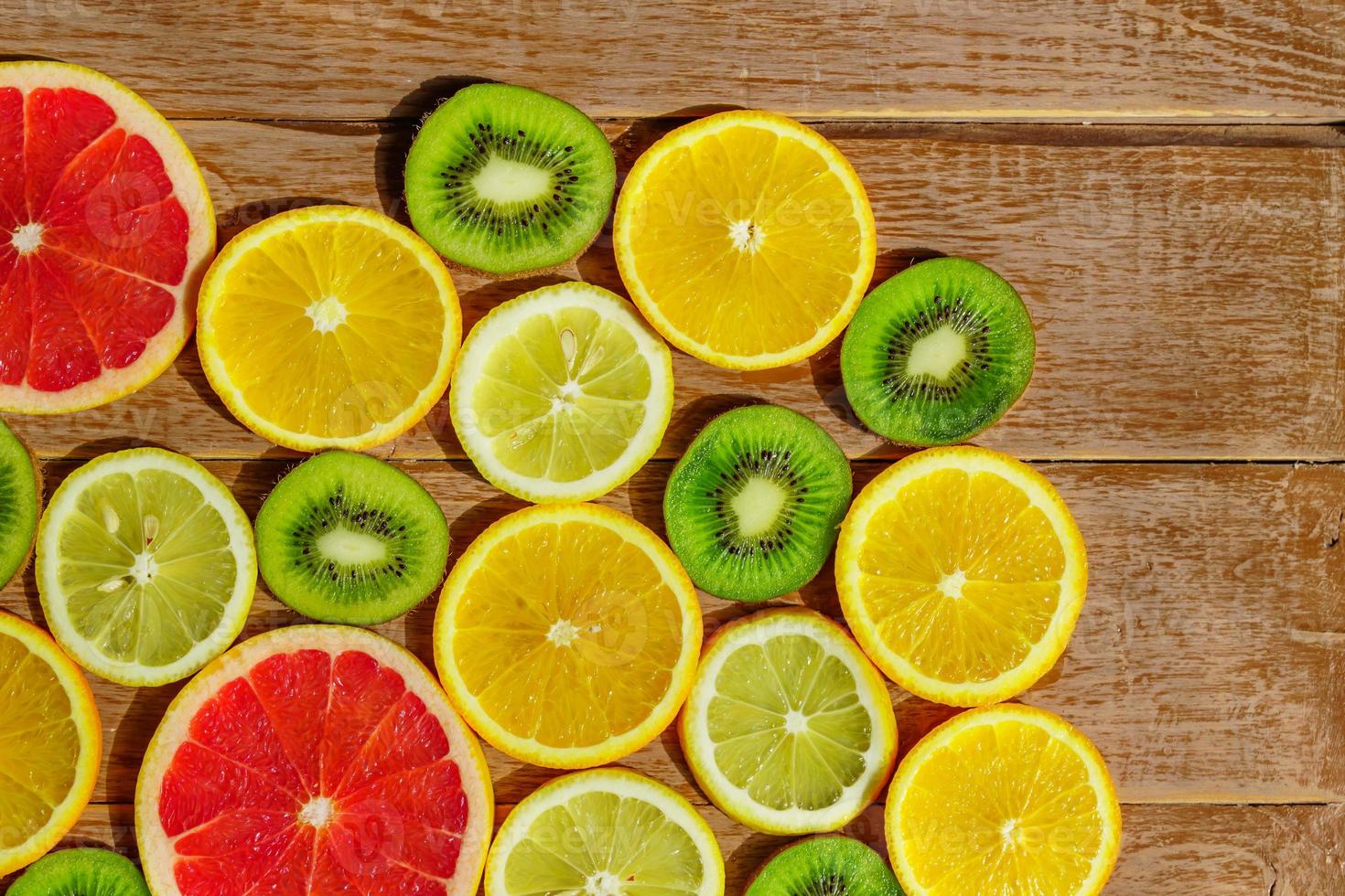 frame with slices of oranges, lemons, kiwi, grapefruit pattern on wooden background. Copy space photo