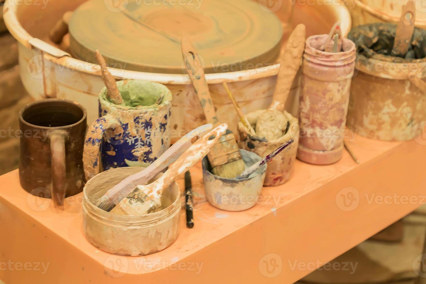 close up of dirty pottery wheel and colorful mud in jars after work photo