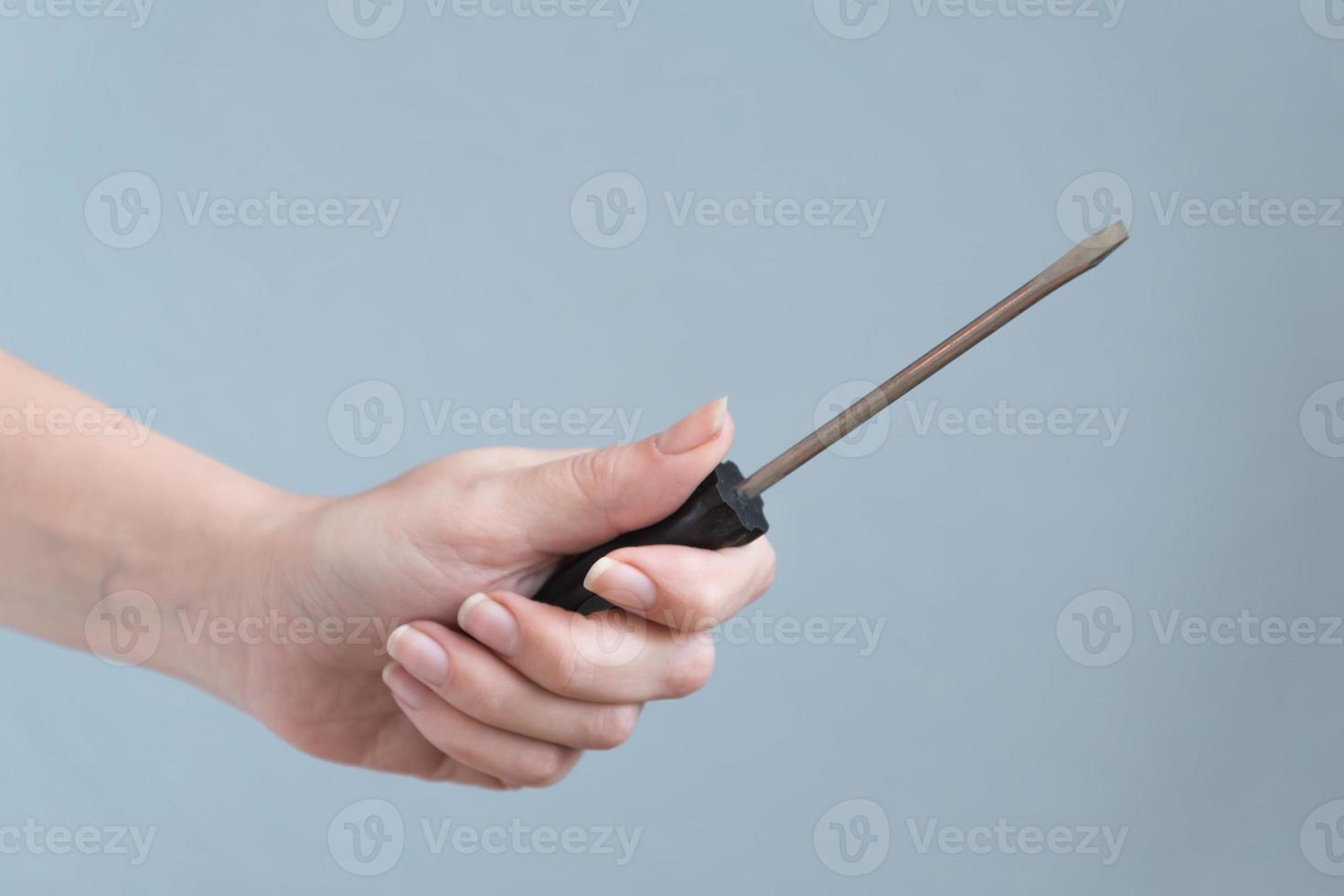 woman holding a screwdriver in her hand on gray background. photo