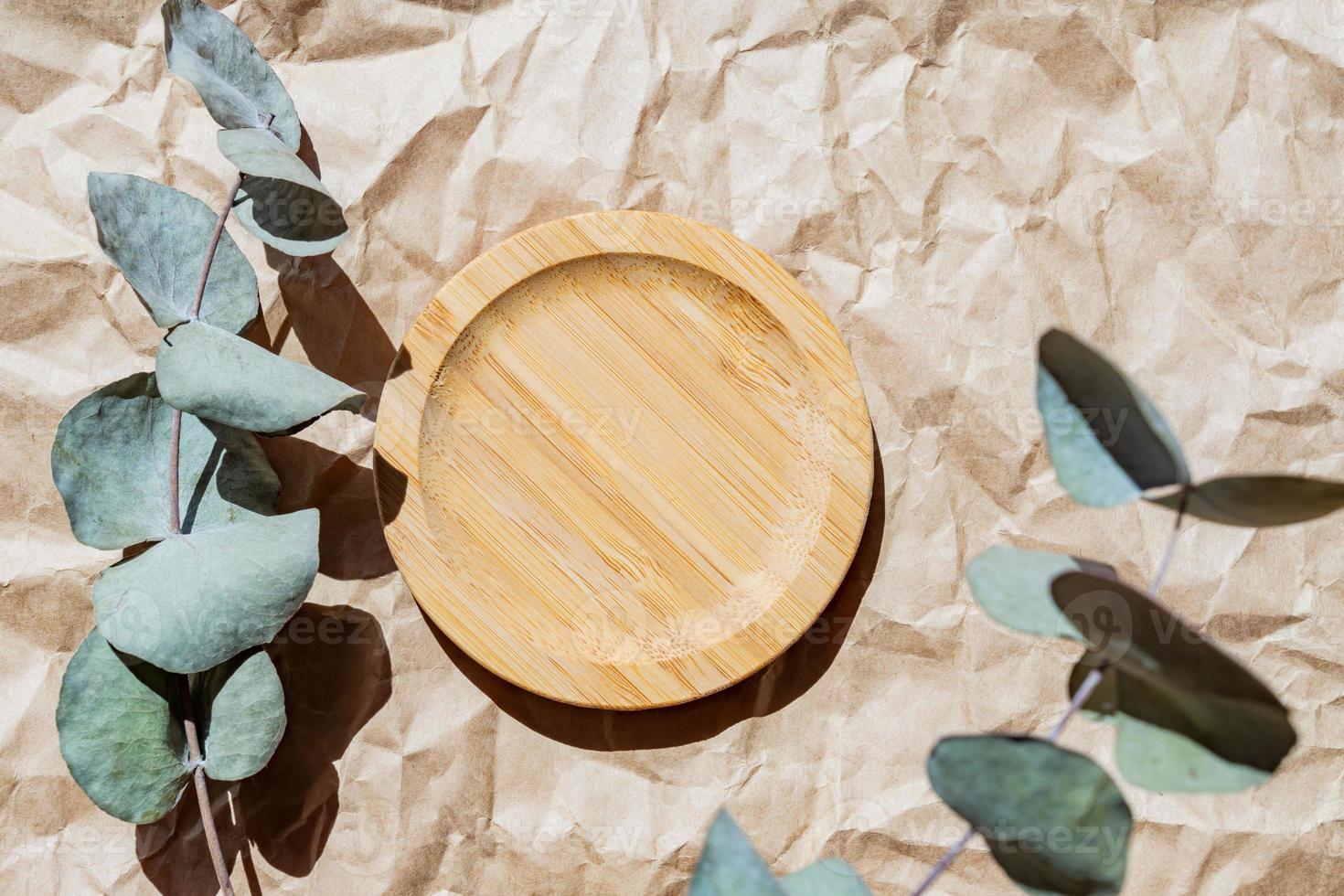 Eucalyptus on wooden tray on paper craft background. Place for text. Blank frame mockups on wooden plate. Modern template. photo