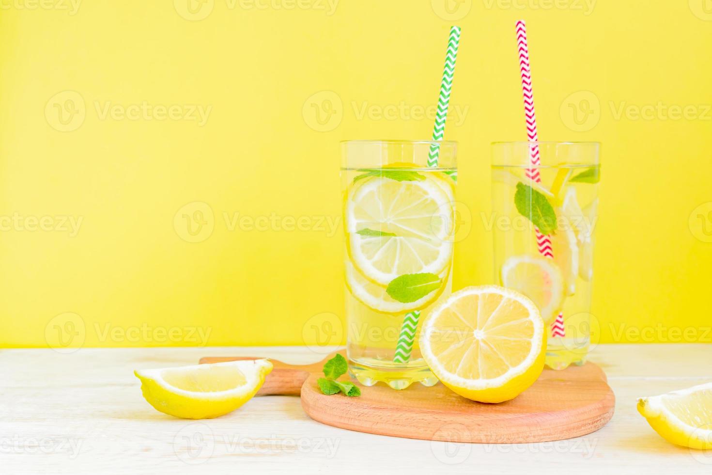 Homemade lemonade with lemon and mint on colored yellow background. Summer cold drink cocktail. Copyspace photo