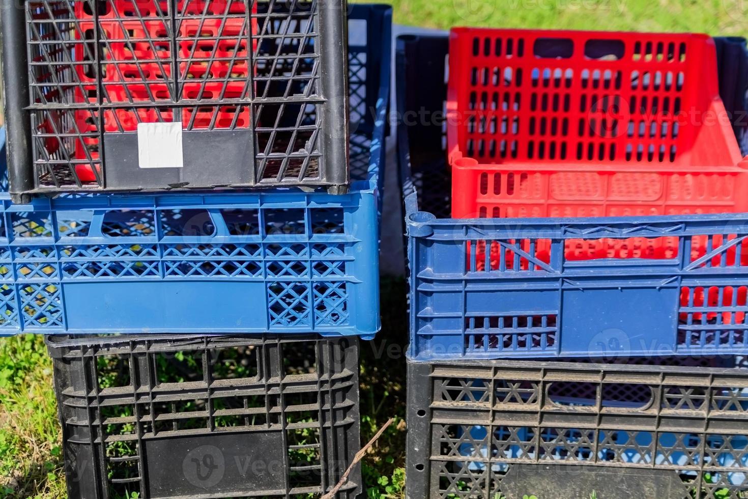 Set of multicolored plastic boxes in the garden. Container for harvest photo