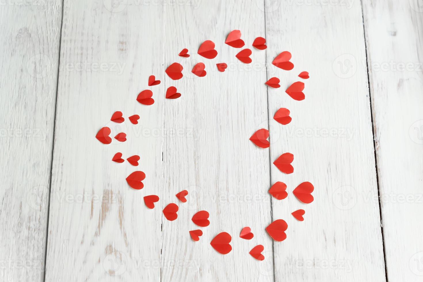 Big red heart made of cut out paper small hearts on wooden backround. Handmaede decoration for Valentine's day. photo