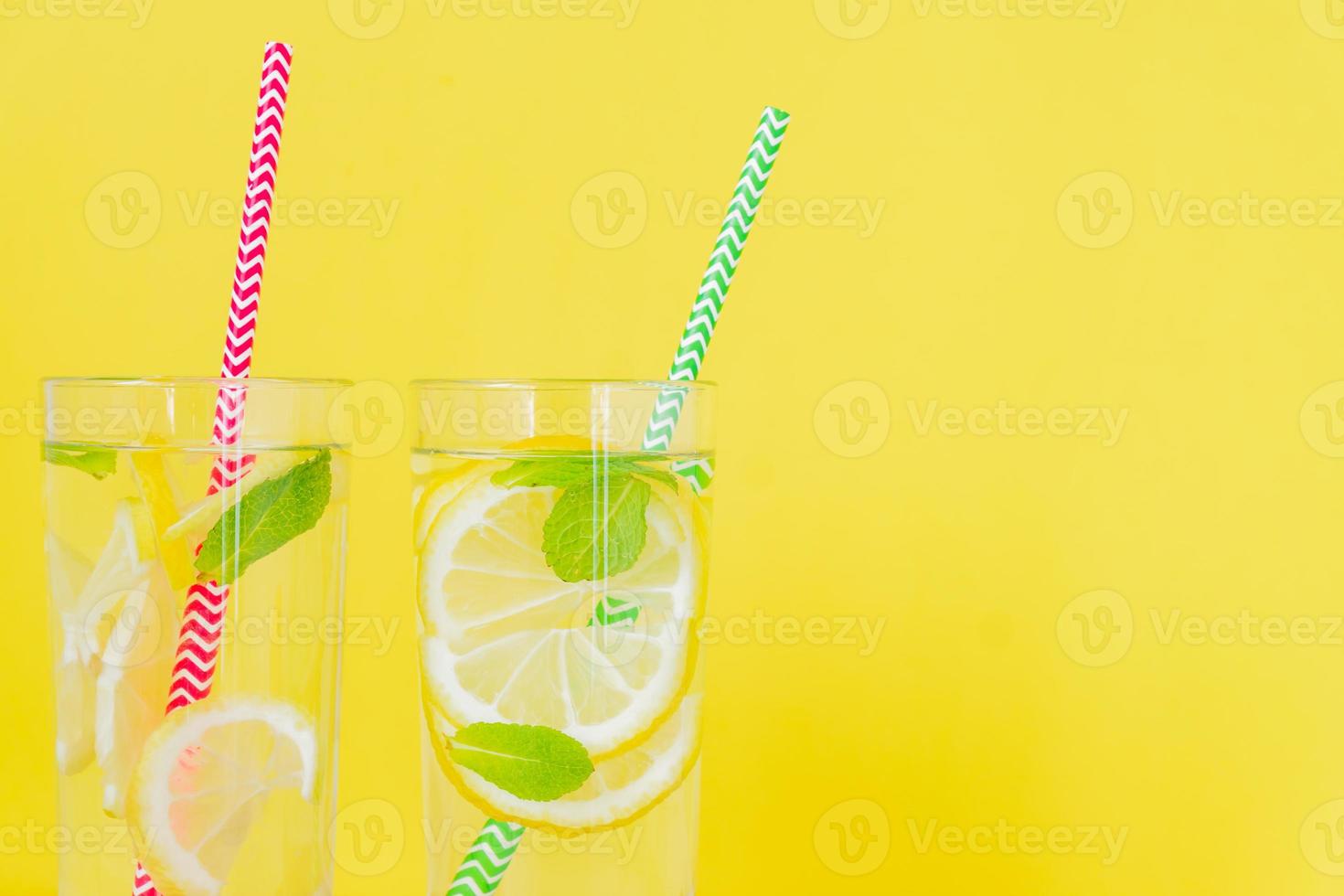 Homemade lemonade with lemon and mint on colored yellow background. Summer cold drink cocktail. Copyspace photo