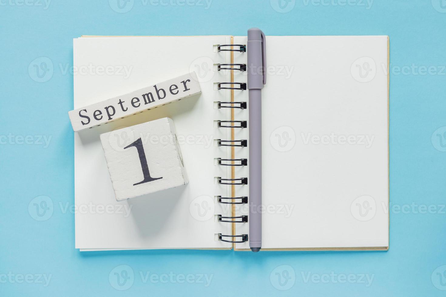 1 de septiembre en un calendario de madera en un libro de texto de estudio sobre fondo azul. concepto de regreso a la escuela foto