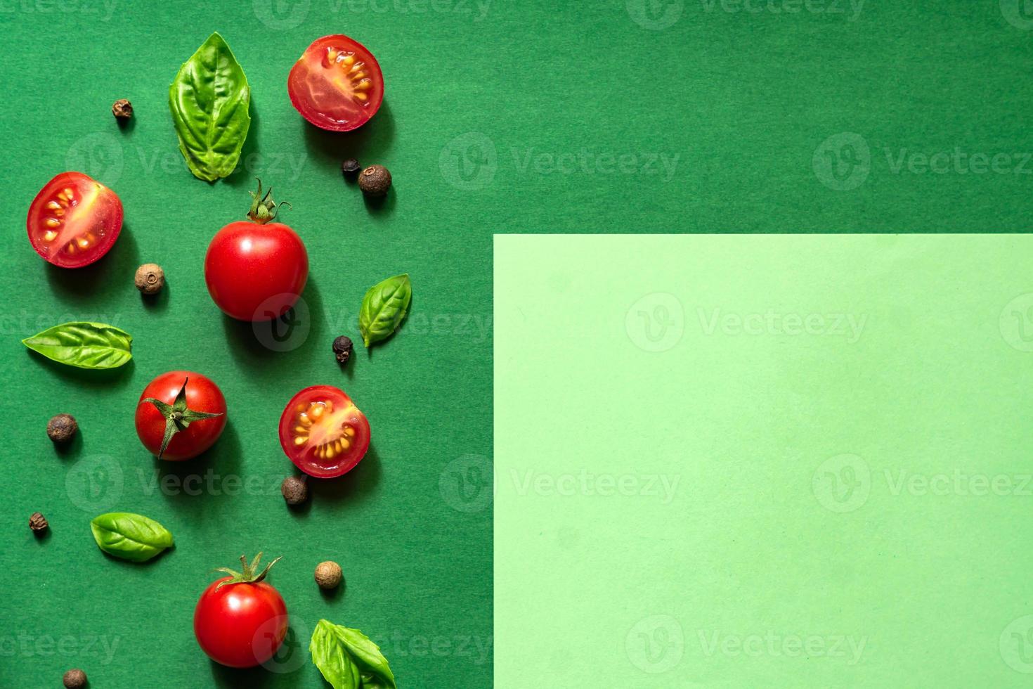 Halved Juicy Cherry Tomatoes and Basil Leaves on a green background. Concept for healthy nutrition. Top view. Copy space. photo