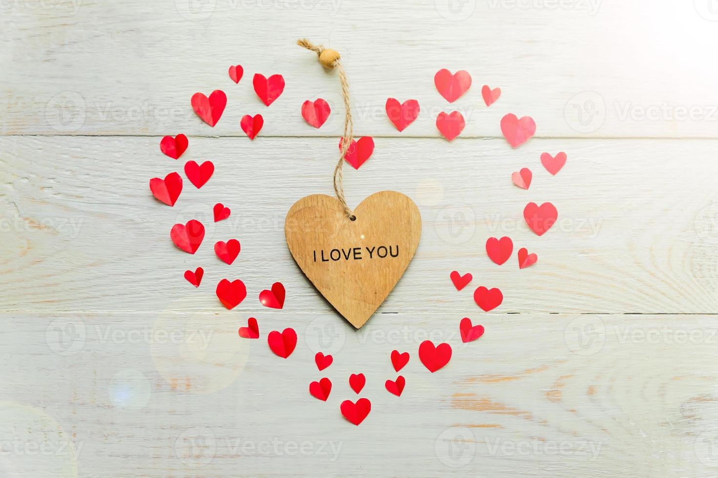 Big red heart made of cut out paper small hearts and wooden heart with I love you inscription on wooden backround. Handmade decoration for Valentine's day. photo
