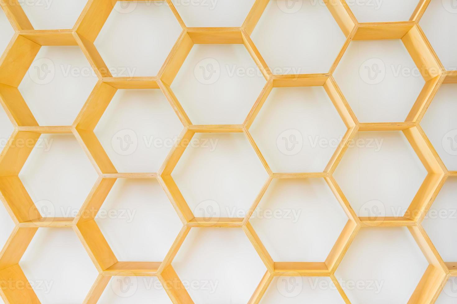 Fragement of interior decoration. Wall with wooden honeycomb shelves. Trendy design. Sunlight shadows. photo