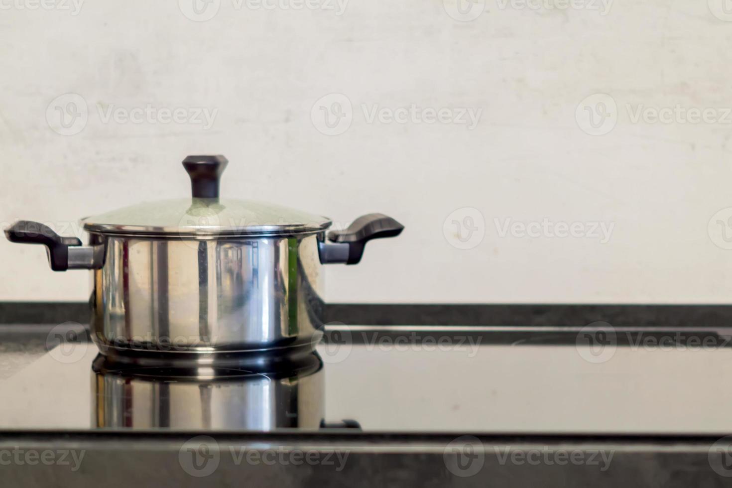 olla cromada en estufa eléctrica, cocina moderna en blanco y negro foto