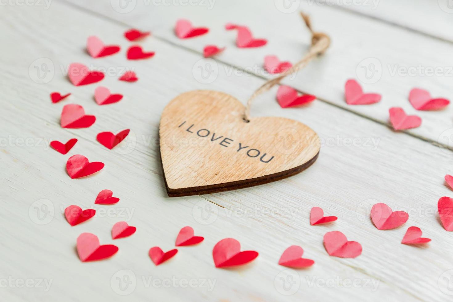 Big red heart made of cut out paper small hearts and wooden heart with I love you inscription on wooden backround. Handmade decoration for Valentine's day. photo