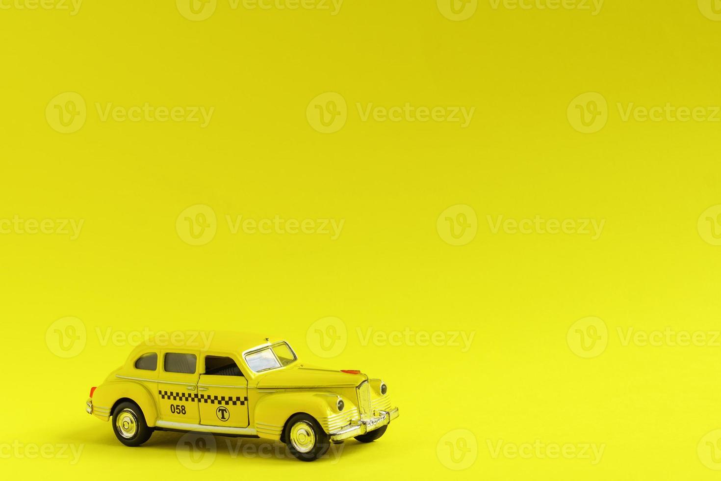 Old retro yellow toy car taxi on yellow background with copy space. Travel concept photo