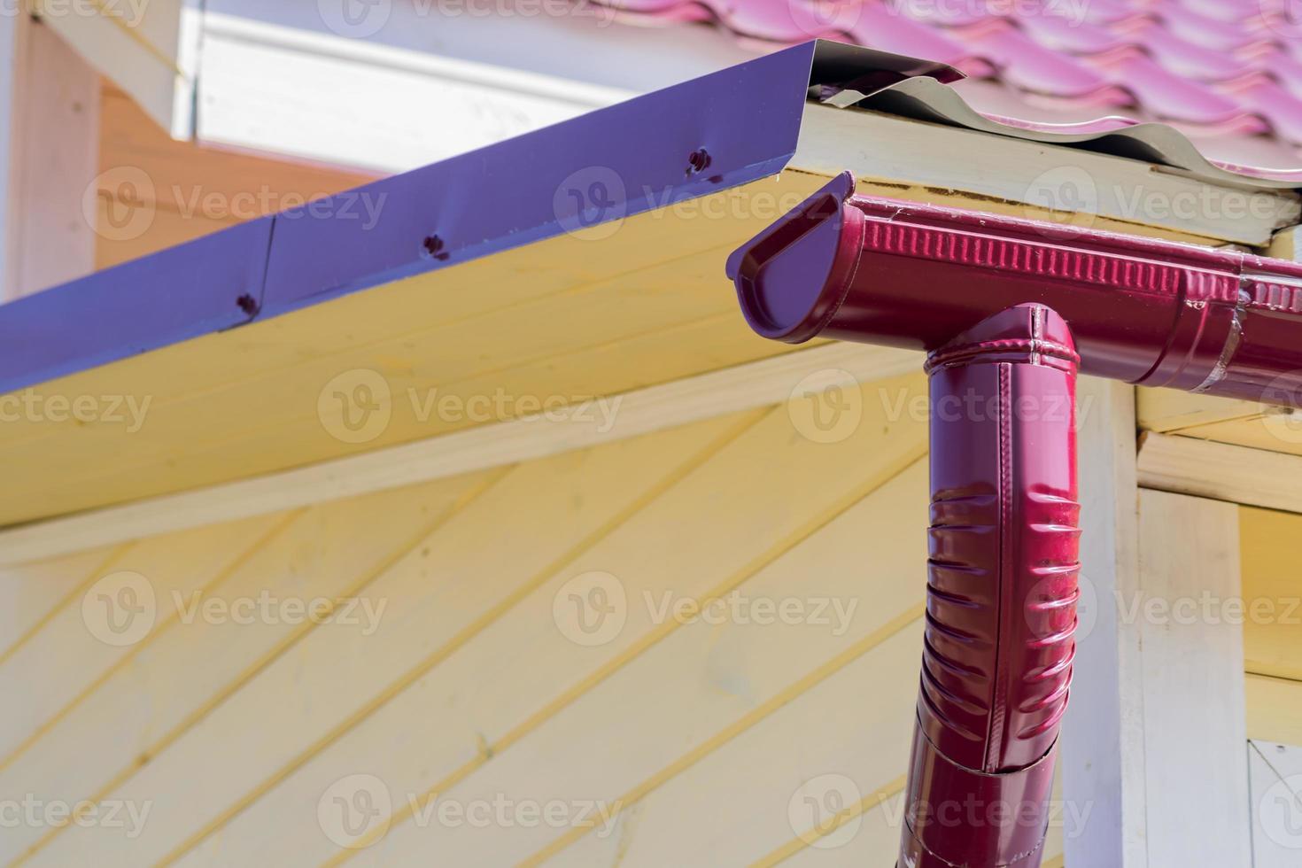 clsoe up of red gutter on the roof top of house photo