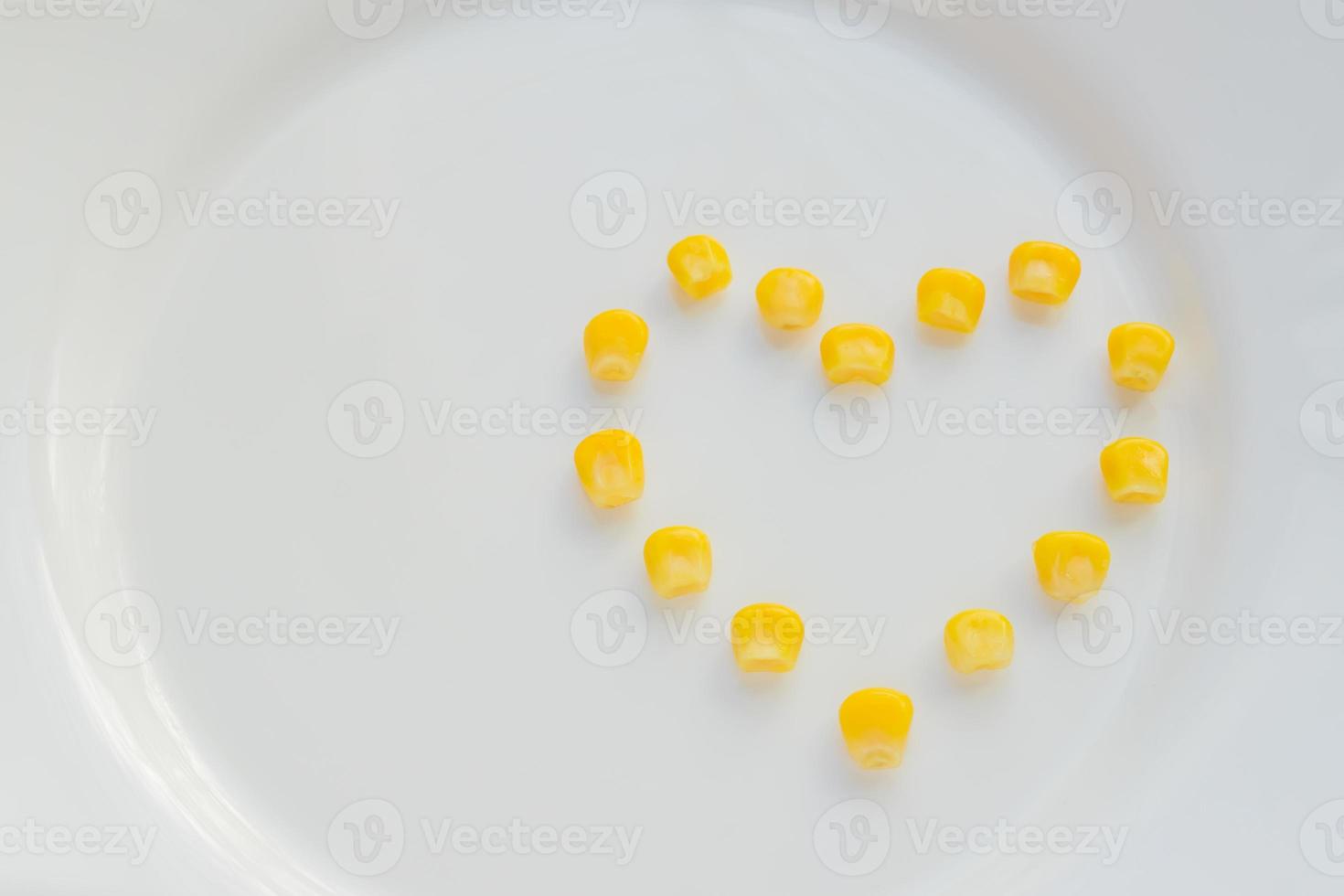 Close up of sweet corn in shape of heart  on white plate. Copy space for your text photo