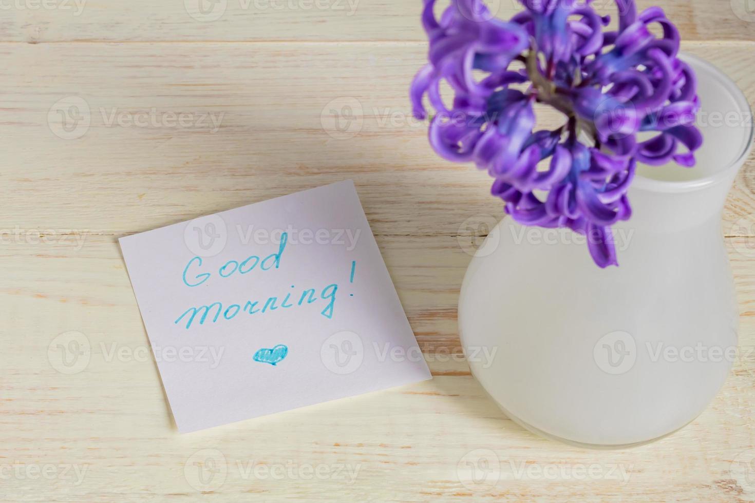 Good morning paper tag and purple hyacinth flower in white vase on wooden table photo