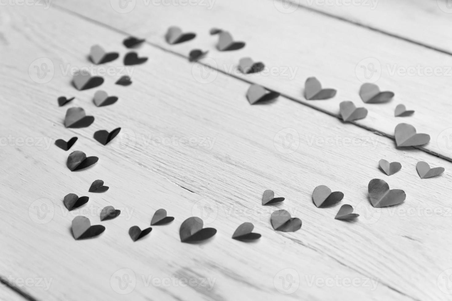 Big heart made of cut out paper small hearts on wooden backround. Handmaede decoration for Valentine's day. Black and white photo