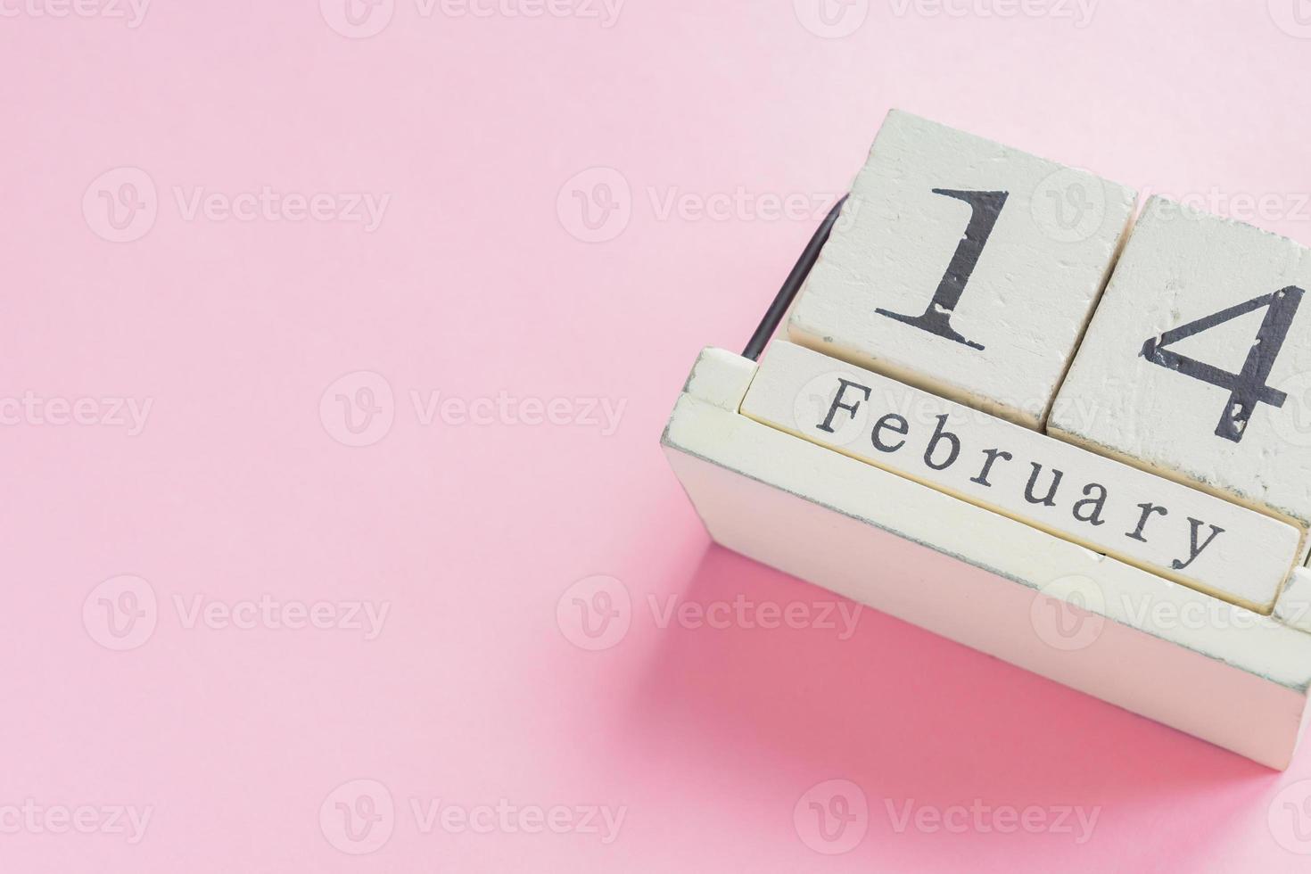 concepto de día de san valentín y vacaciones - cierre del calendario de madera con fecha del 14 de febrero sobre fondo rosa foto