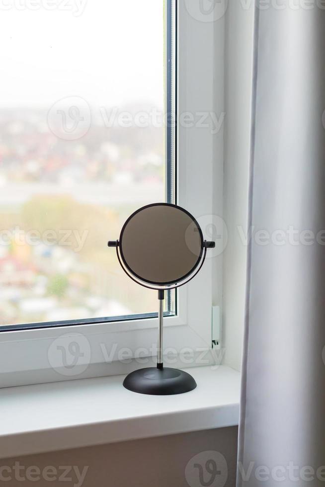 black round make up mirror on window sill photo