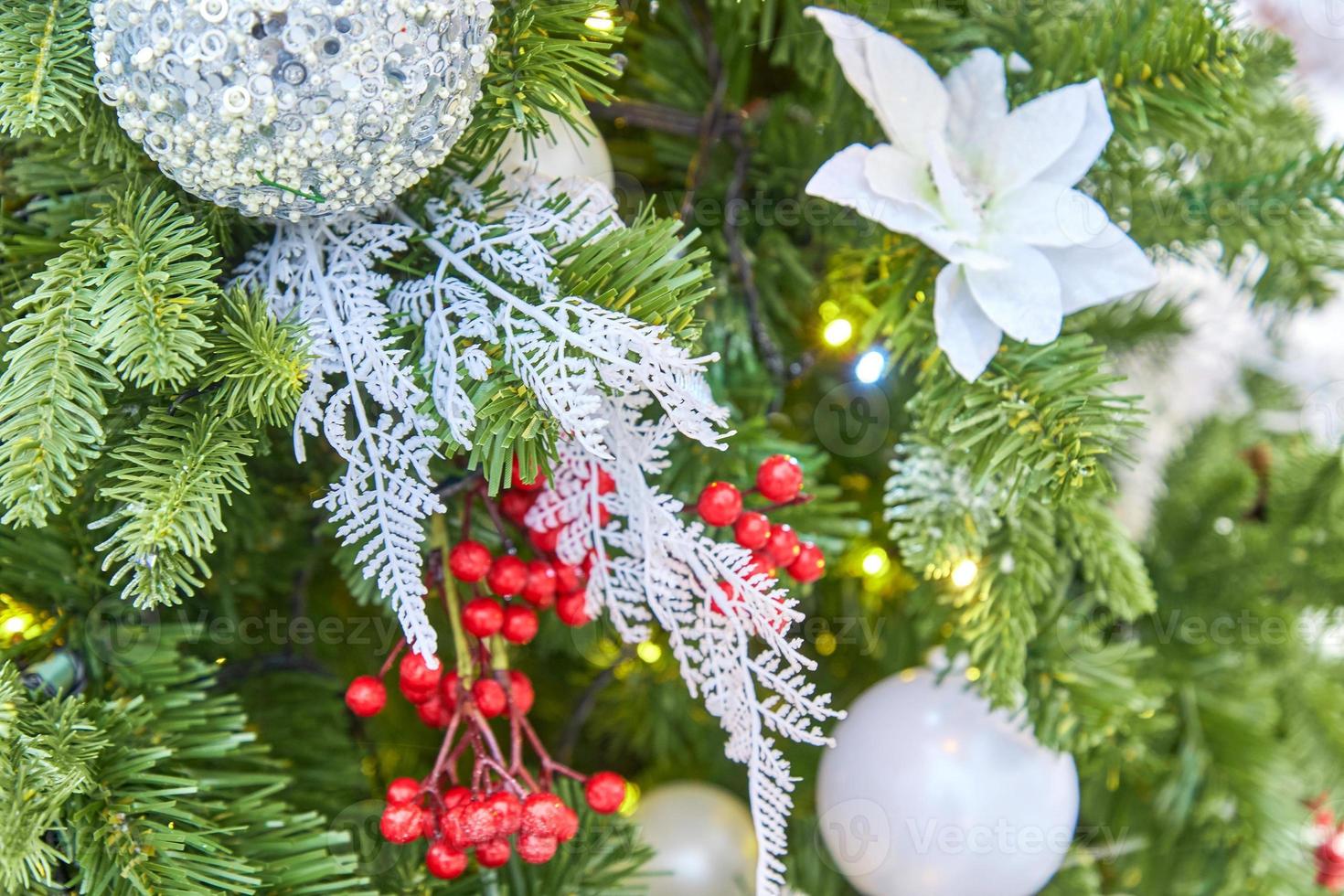close up of christmas tree decorated with silver sparkling balls and garland with lights on. Festive background with copy space for your projects photo