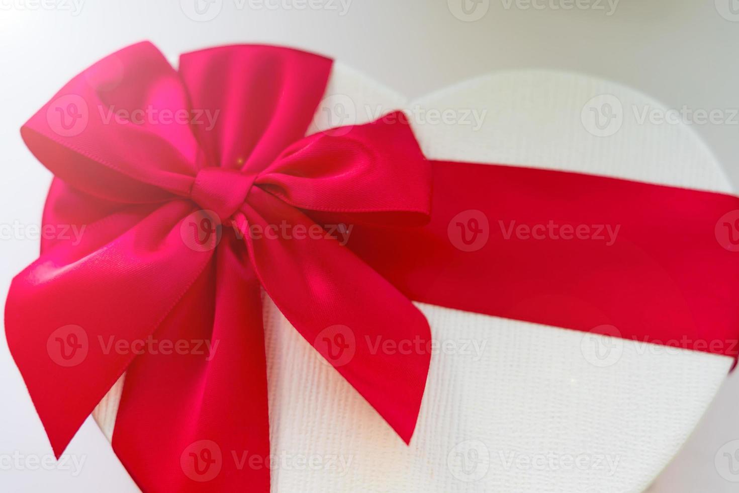 gft box in a heart shape with red silk bow close up photo