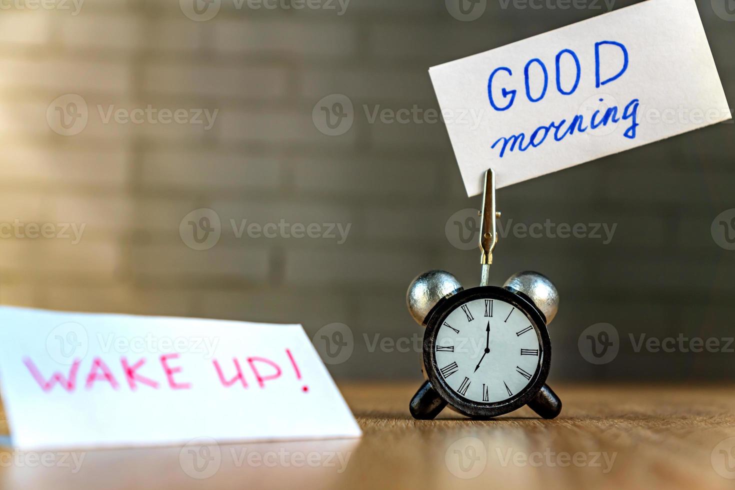 Alarm clock and banner with handwritten phrase good morning on wooden table. Time management concept. photo