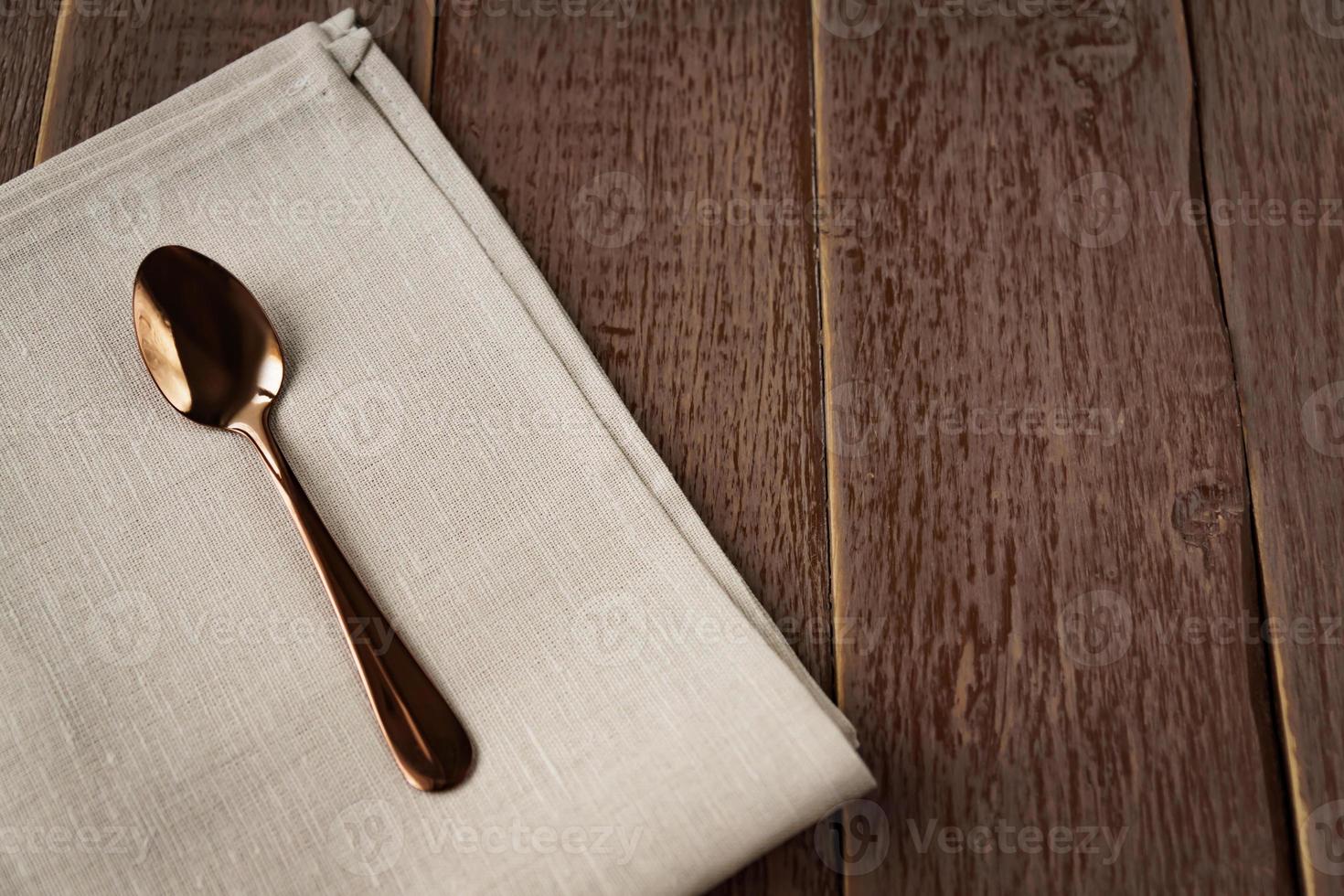 Top view of cloth napkin of beige color and served tea spoon on wooden table. photo